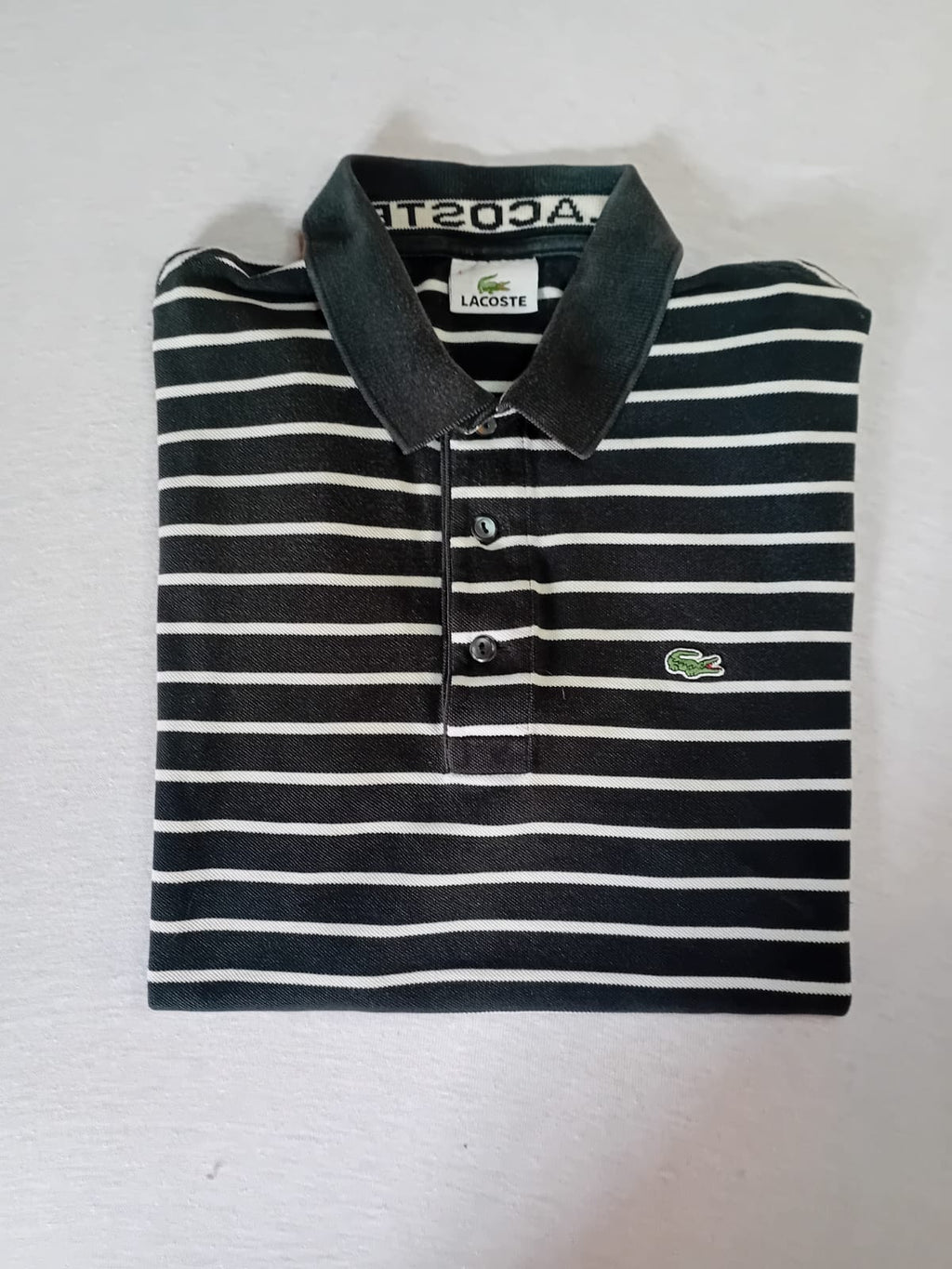 Polo Lacoste fines rayures noir blanc – vue pliée face